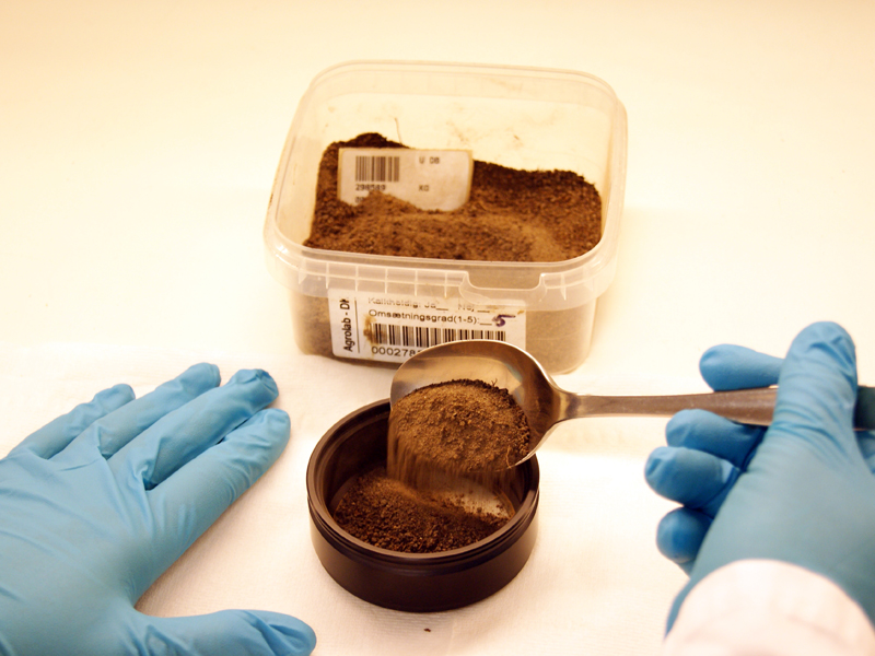 Spoon scooping soil sample from container