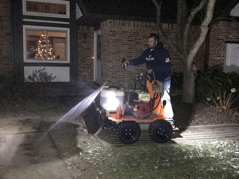 Man spraying salt solution on sidewalk