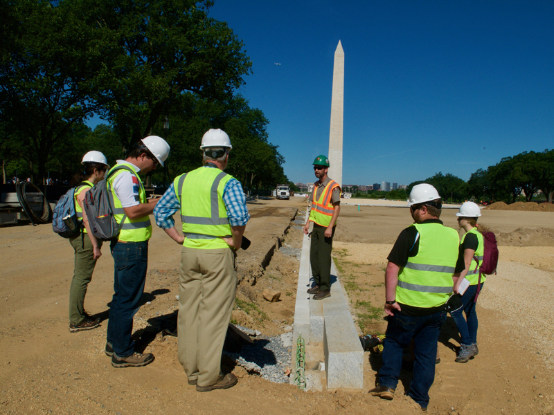 People in construction vests with Washington Monument in background.